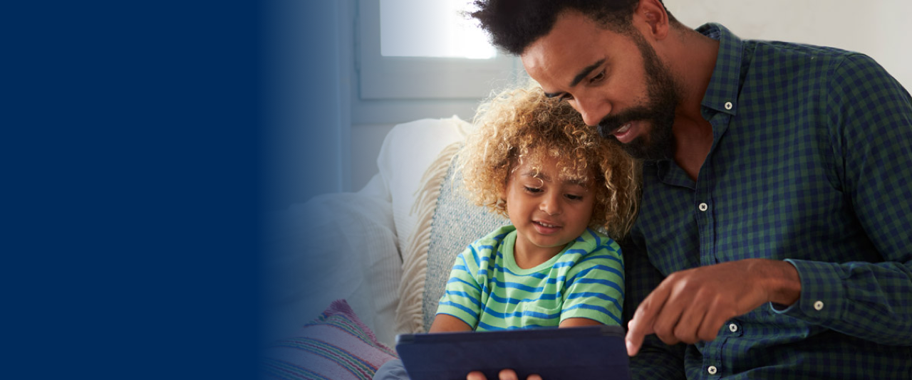 father and son sitting on sofa looking at a tablet